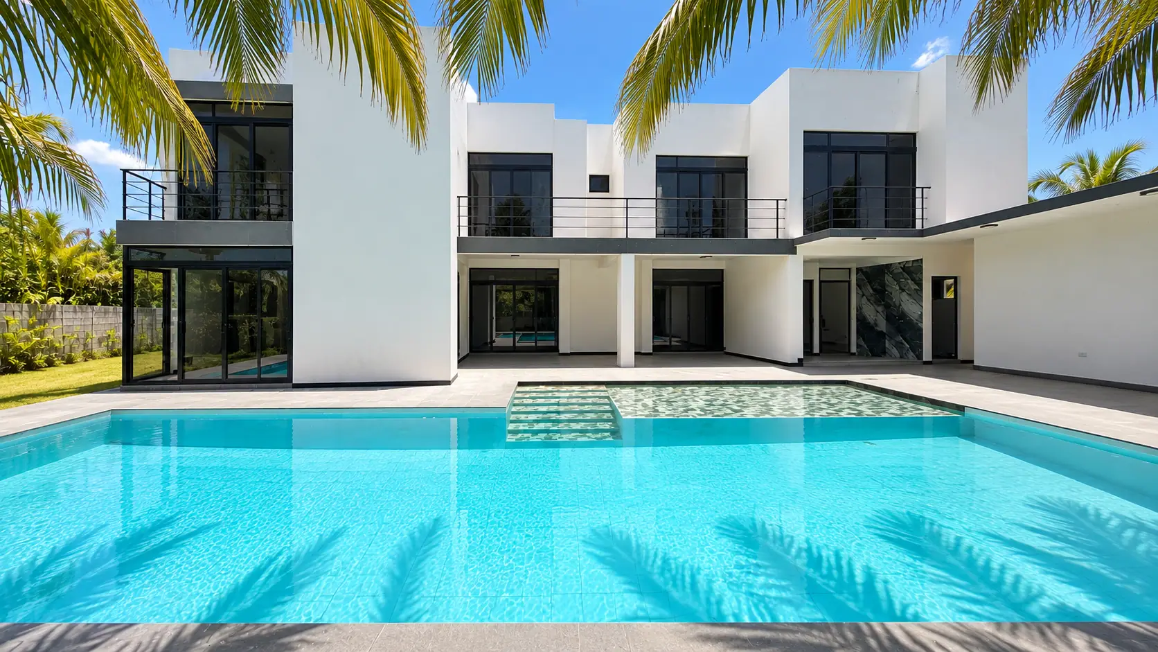 Fachada blanca de Coco Beach con piscina y palmeras