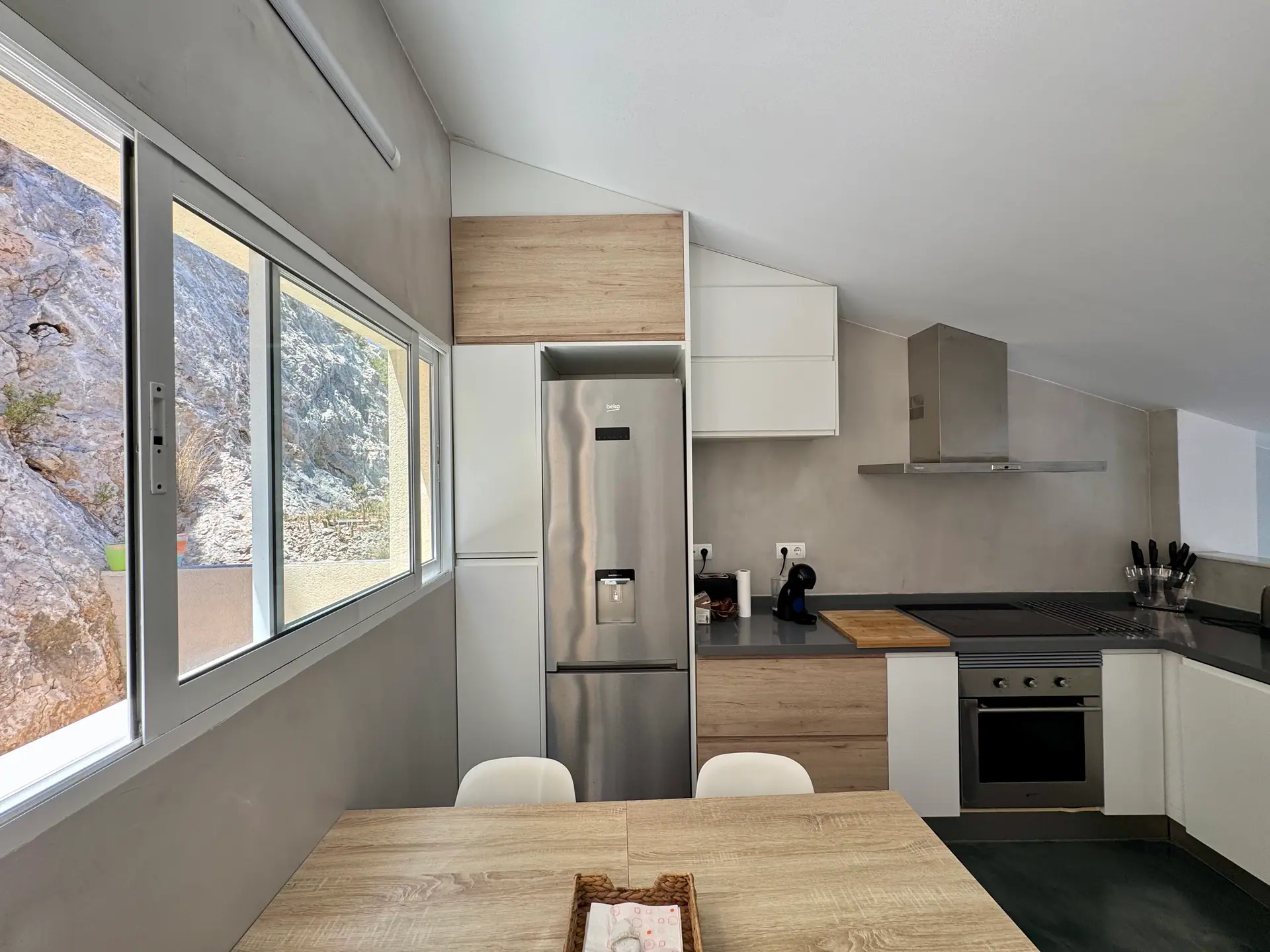Cocina moderna con ventanal abierto a la roca del acantilado