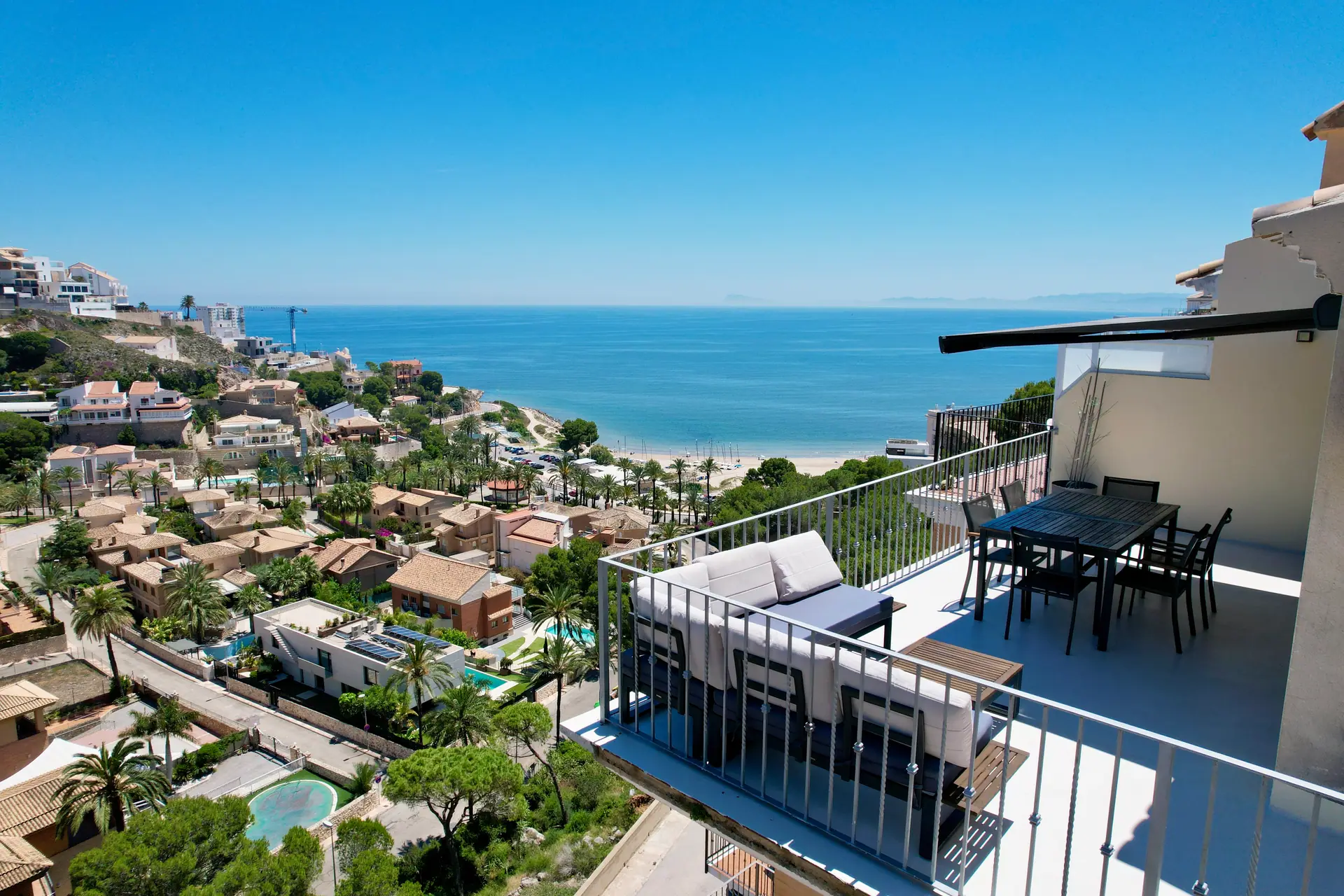 Terraza con sofá y comedor exterior frente al mar